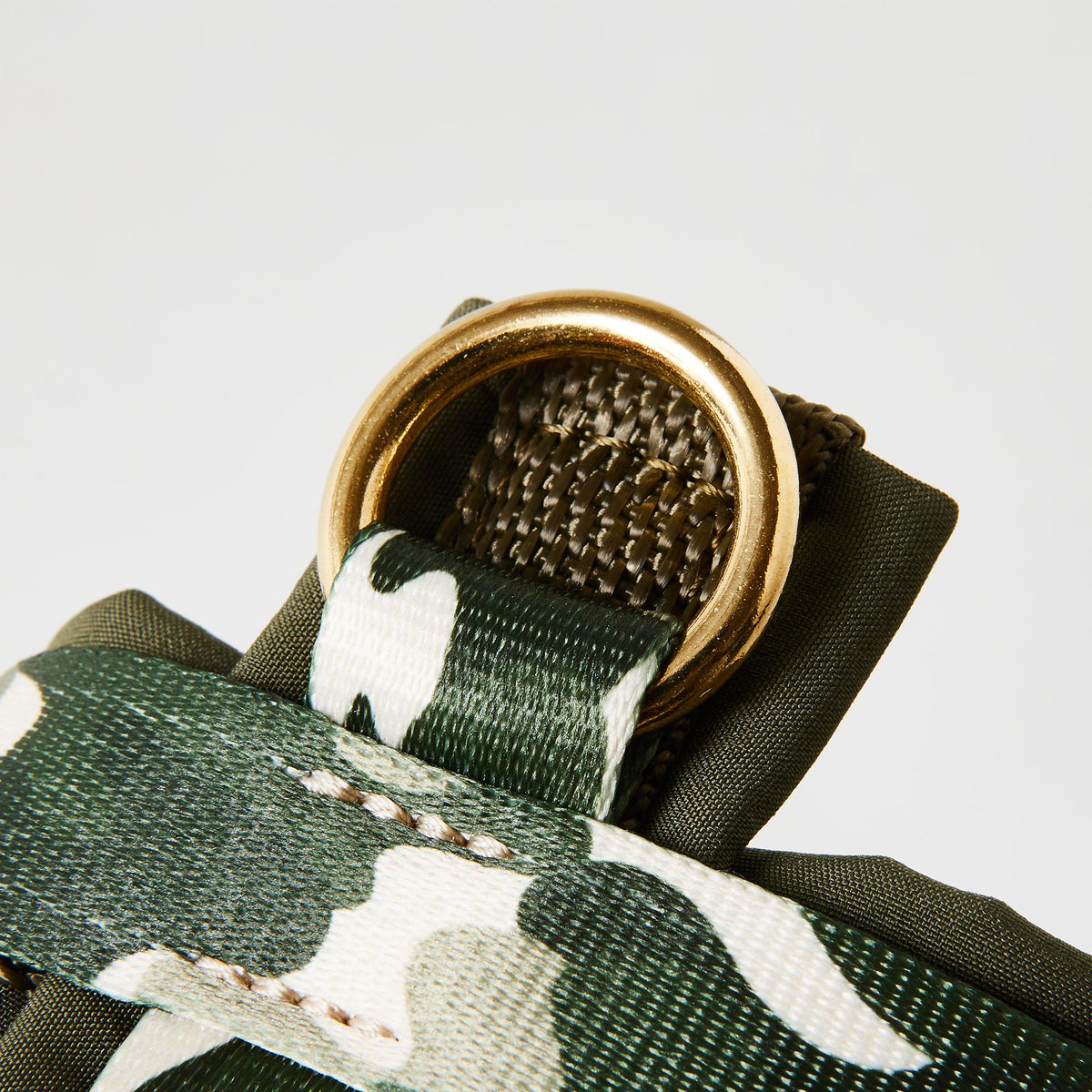 Nahaufnahme verstellbares Hundegeschirr „Entdecker“ mit gepolstertem goldfarbenem O-Ring zum Einhaken des Karabiners und tarnfarbenem Camouflage-Muster.