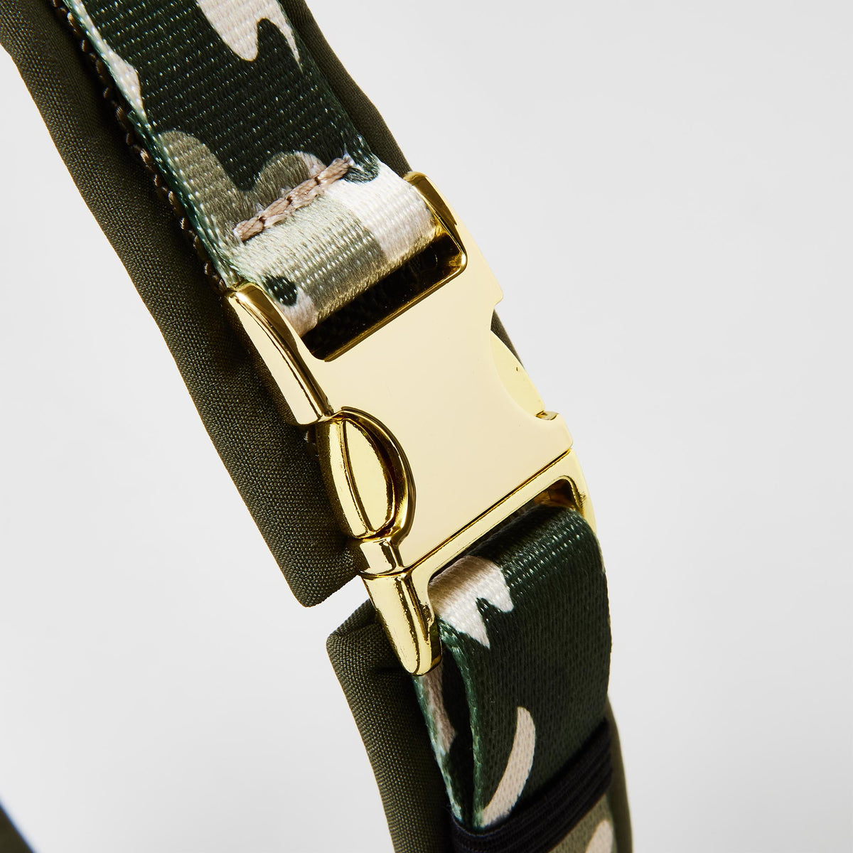 Detail gepolstertes Hundegeschirr „Entdecker“ mit goldfarbener Steckschließe zum Öffnen und Schließen, Gurtband im Camouflage-Look.