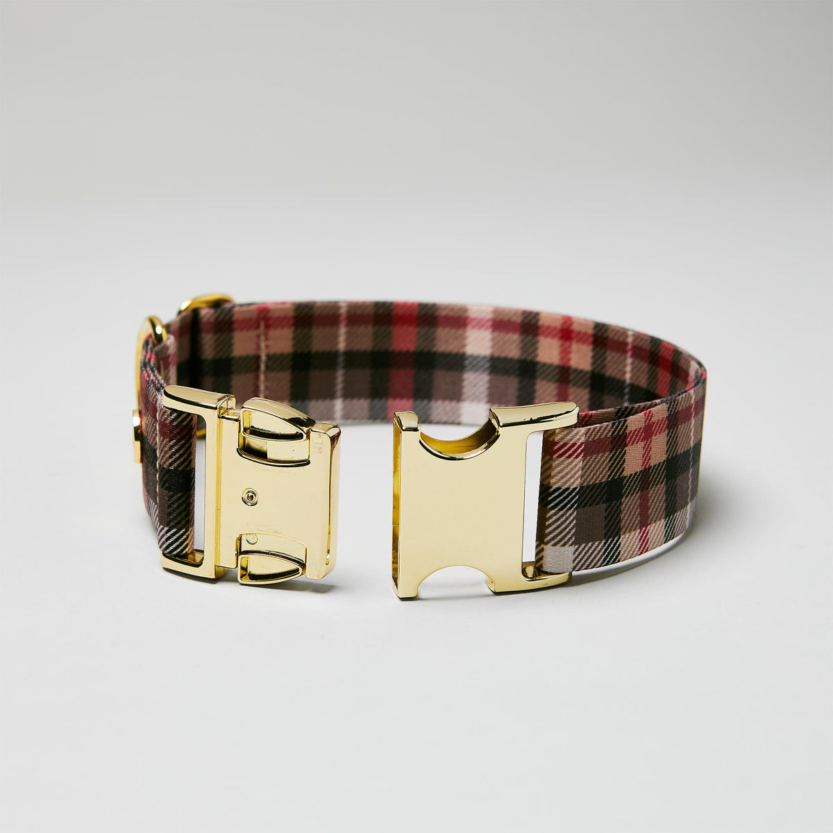 Detailaufnahme verstellbares Halsband „Flaneur“ mit geöffneter goldfarbener Steckschließe, Gurtband mit Karomuster.