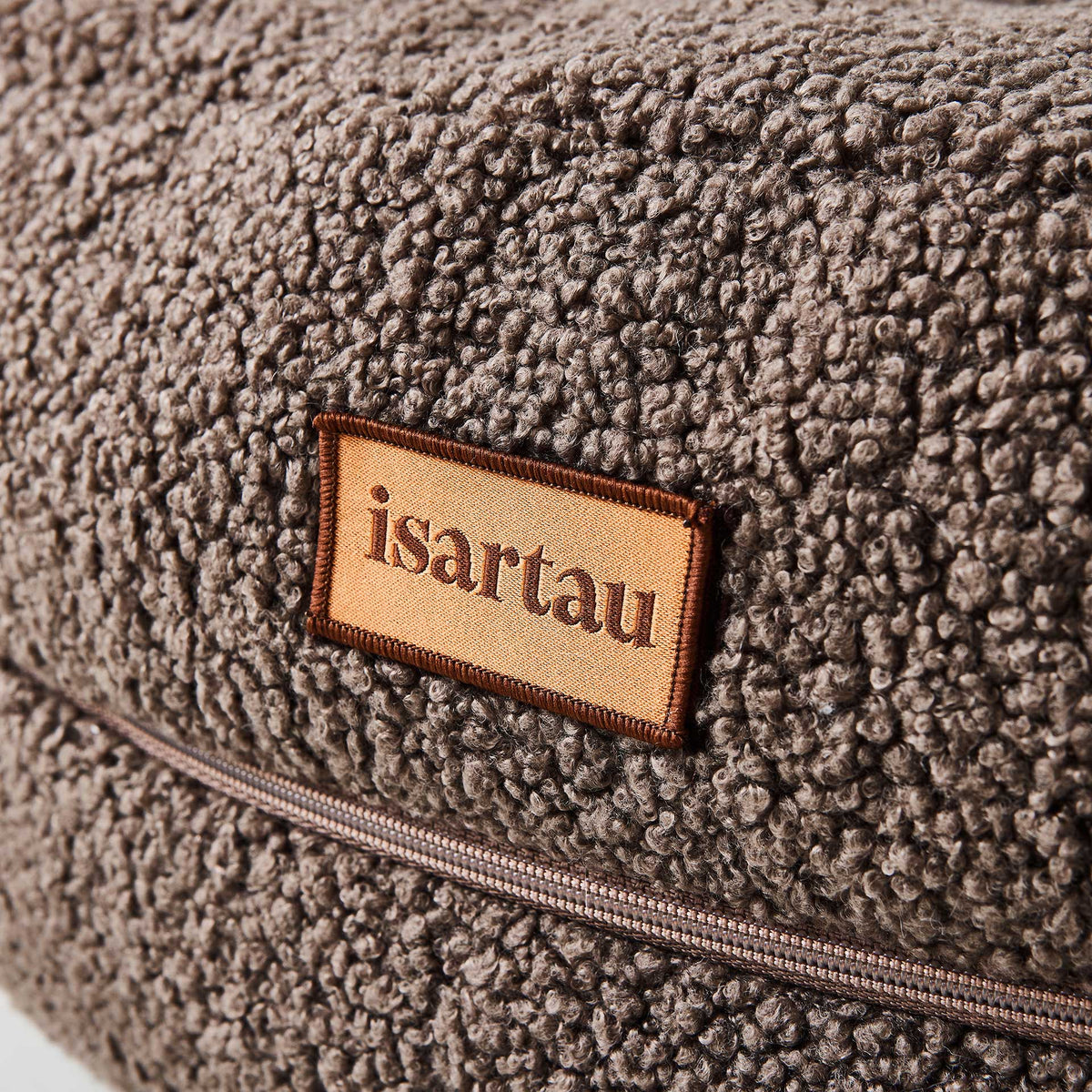 Detail Hundebett Bagelbettchen mit abnehmbarem braunen Teddystoffbezug, Fokus auf isartau Logo