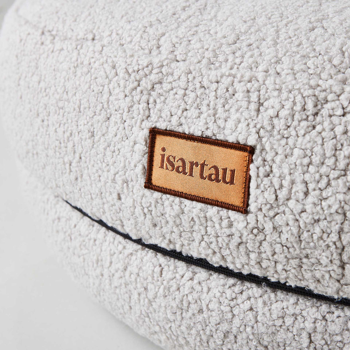 Detail Hundebett Bagelbettchen mit abnehmbarem hellgrauer Teddystoffbezug, Fokus auf isartau Logo