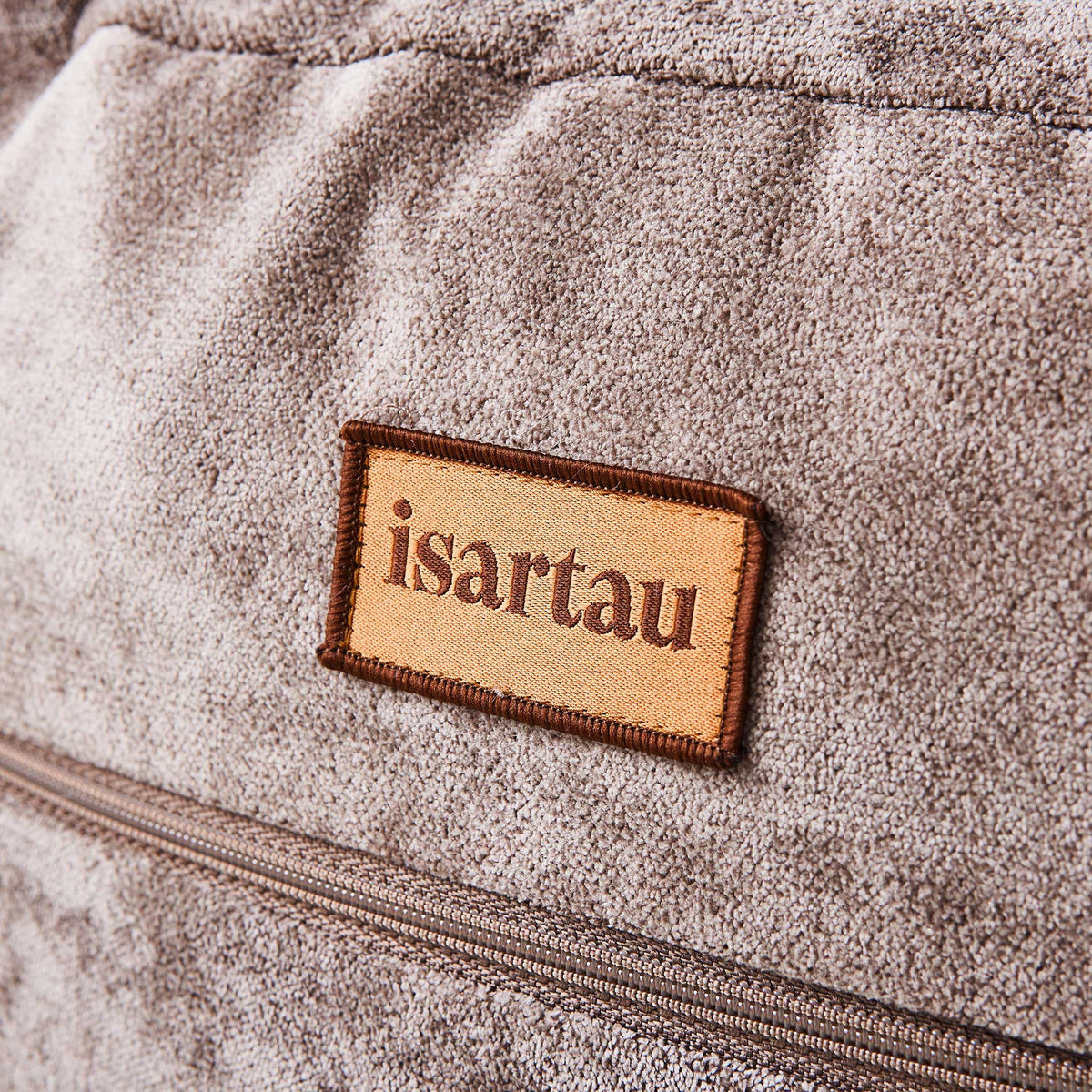 Detail Hundebett Bagelbettchen mit abnehmbarem taupefarbener Veloursbezug aus Polsterstoff, Fokus auf isartau Logo